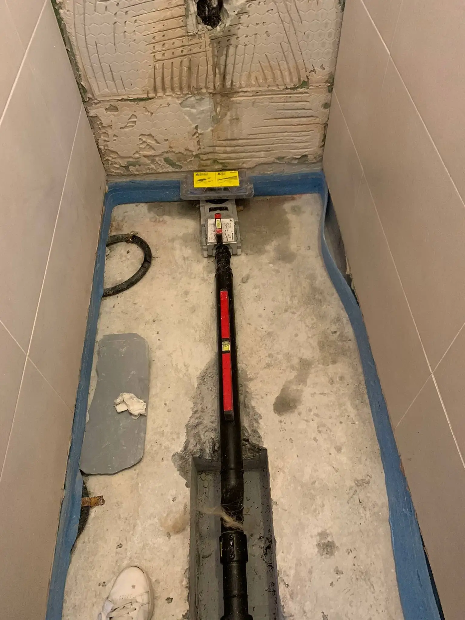 Tranchée dans une ancienne douche pour remplacer la canalisation d’évacuation