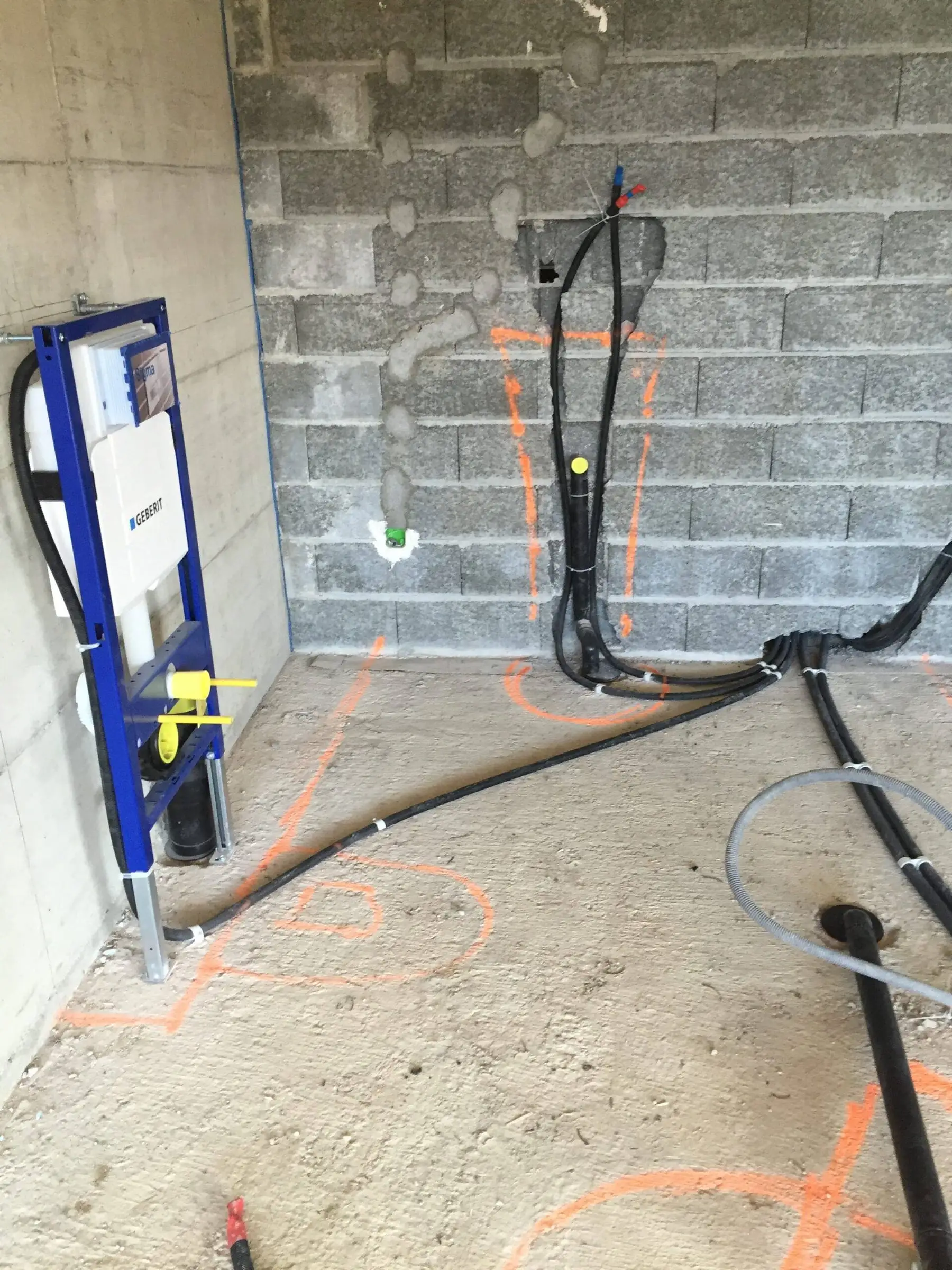 Bâti-support de WC suspendu fixé contre un mur en briques, conduites au sol