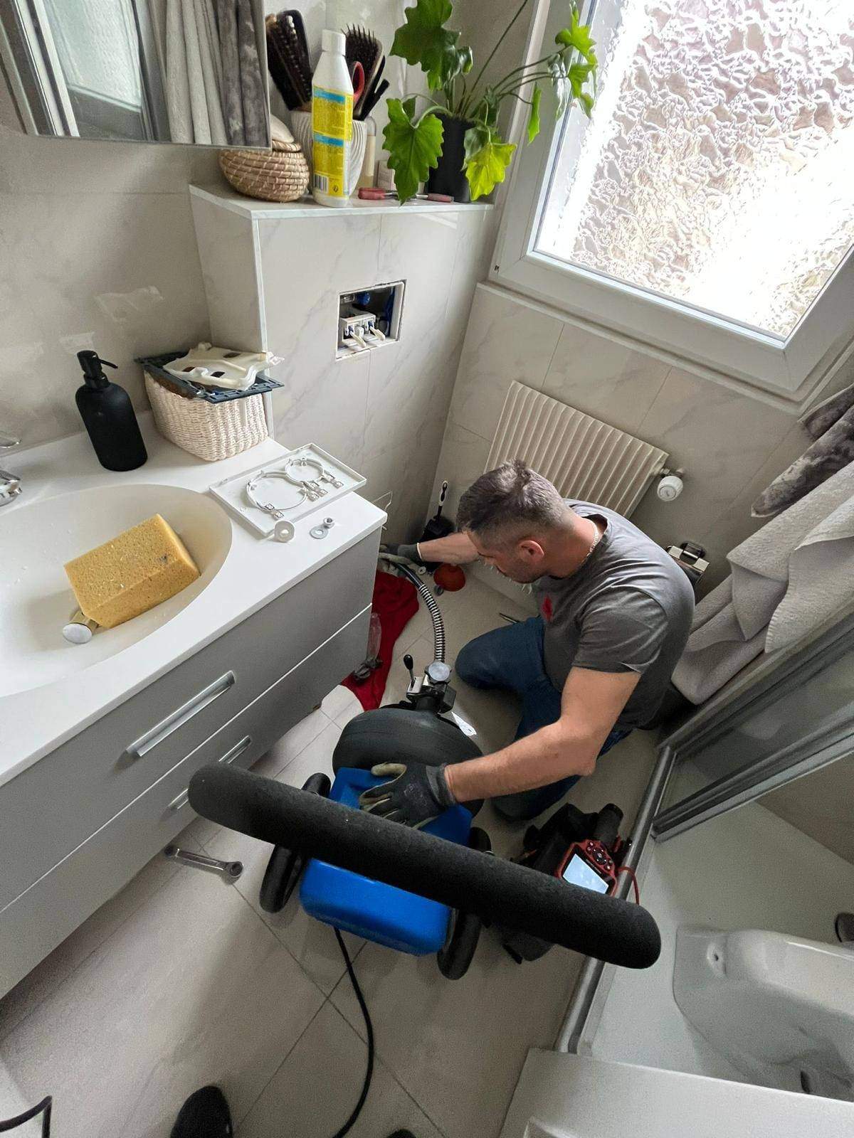 Plombier Swiss Plomberie débouchant une canalisation de salle de bain avec une machine à spirale