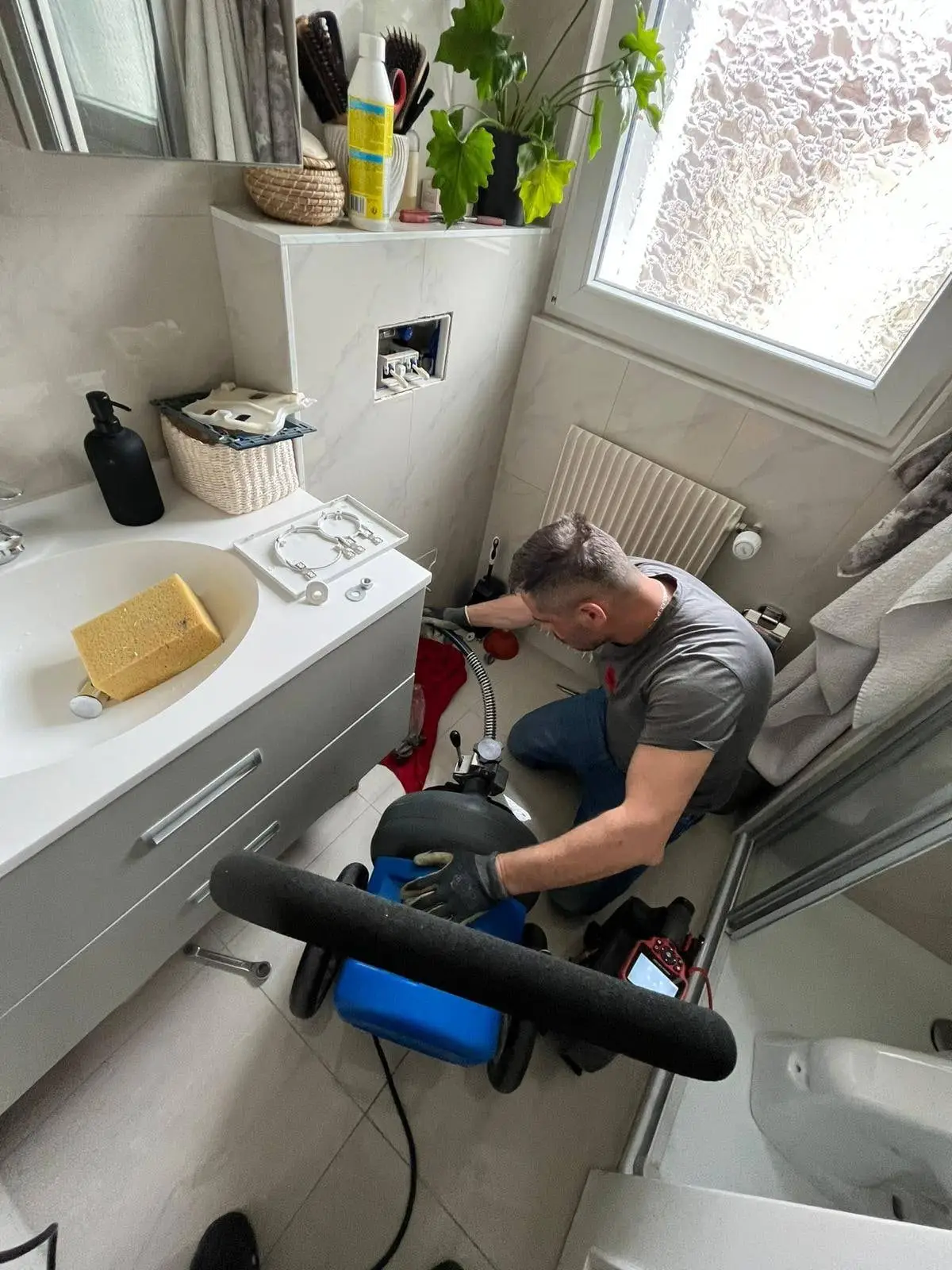 Plombier débouchant une canalisation de salle de bain avec une machine à spirale
