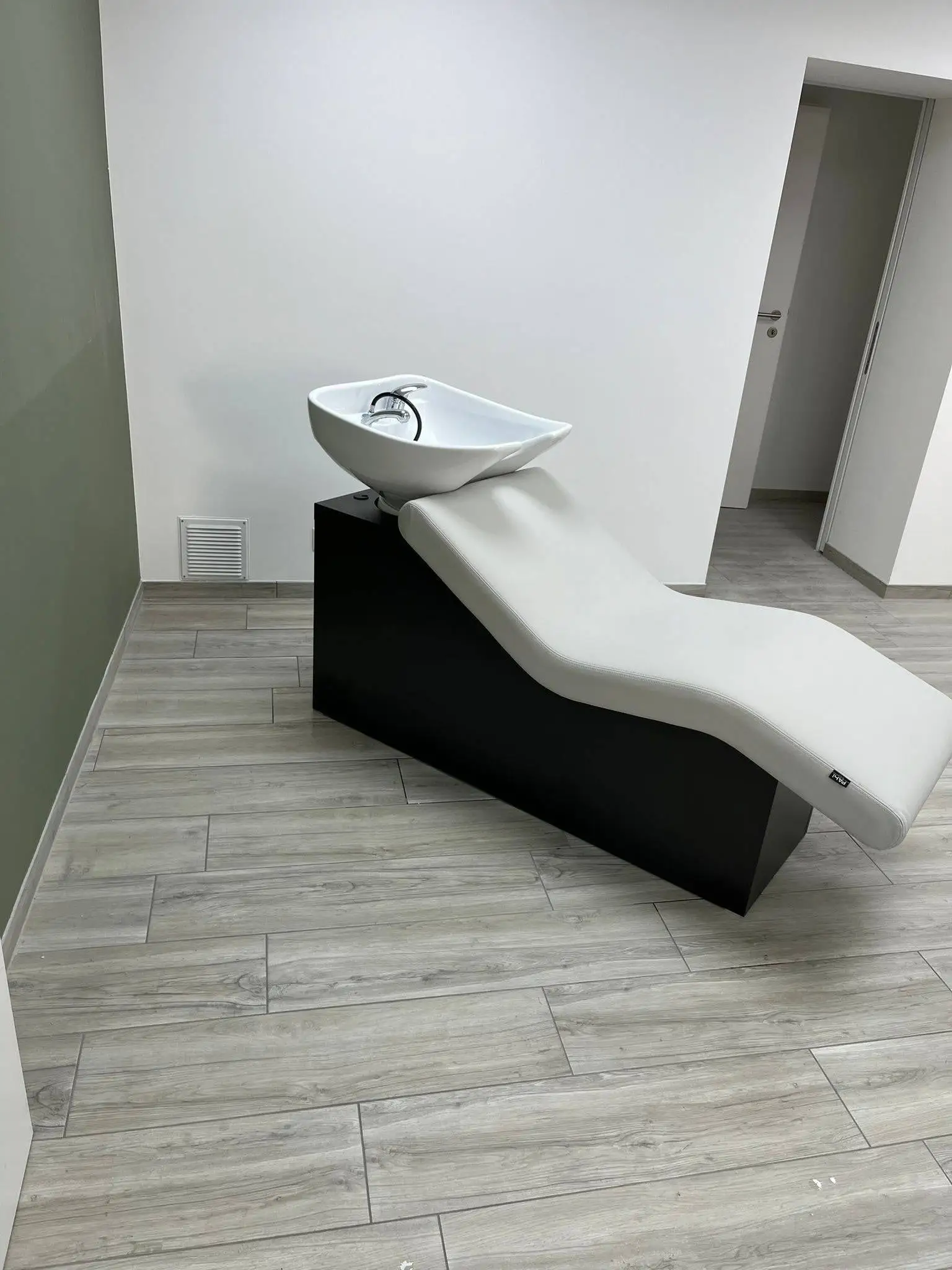Bac de lavage de spa installé sur un meuble noir, dans un local au sol imitation bois