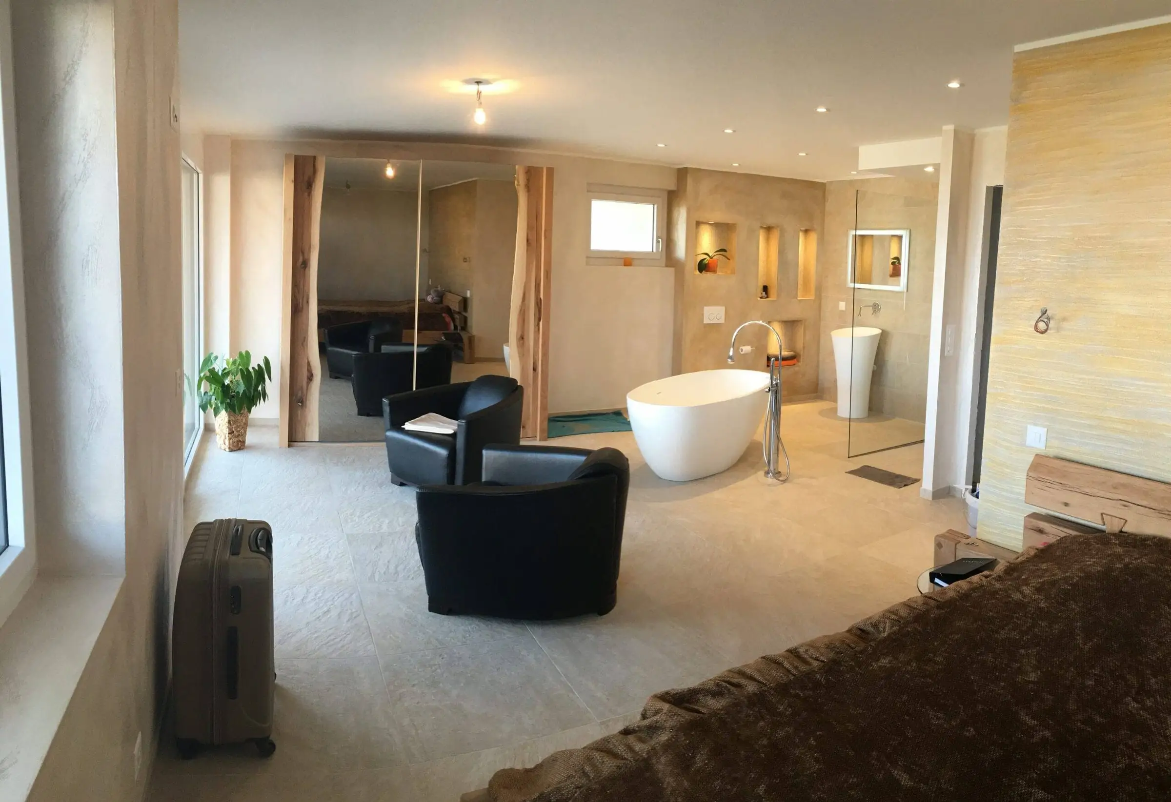 Suite parentale ouverte avec baignoire îlot blanche, vasque sur colonne et fauteuils